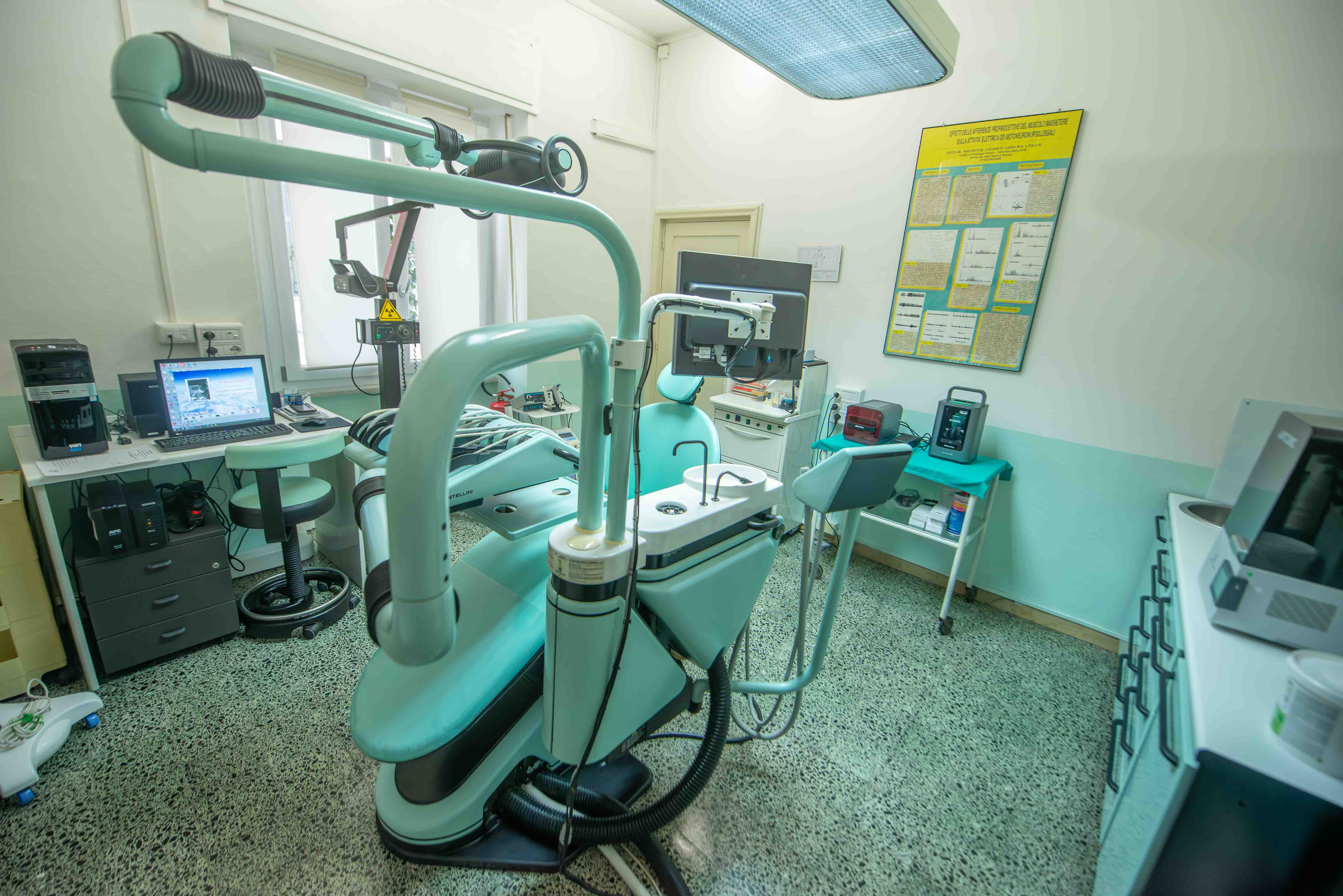 Stanza turchese con poltrona, monitor e apparecchiature cliniche